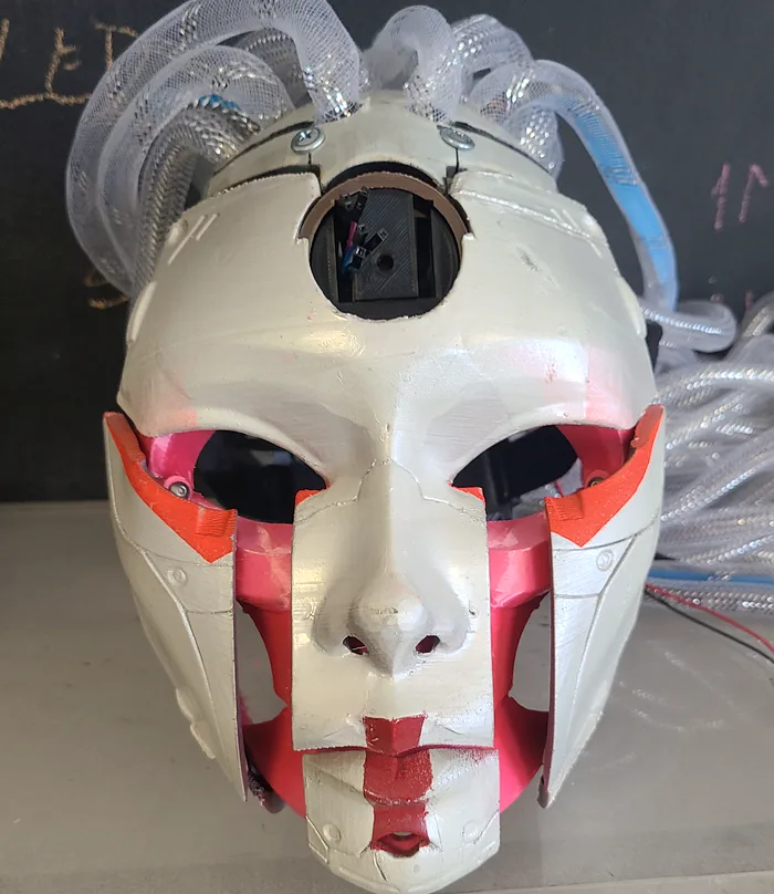 ROSHIE's robotic head: a white sculpted face with red and pink inner workings